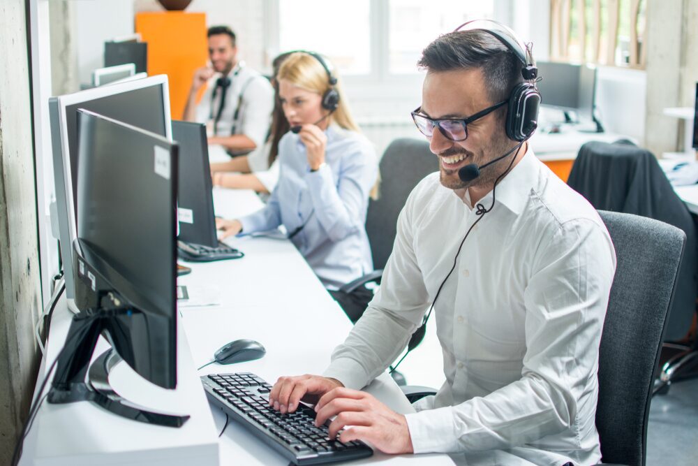 A male employee is happily talking with his client on the phone